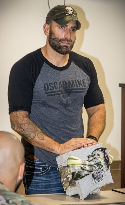 Former Army Sgt. Earl Granville listens to an audience member's question while touching a cinderblock that symbolizes the need to not try to hold all of life's burdens on one's own, during a resilience presentation for the 75th Innovation Command at Ellington Field Joint Reserve Base, Texas.