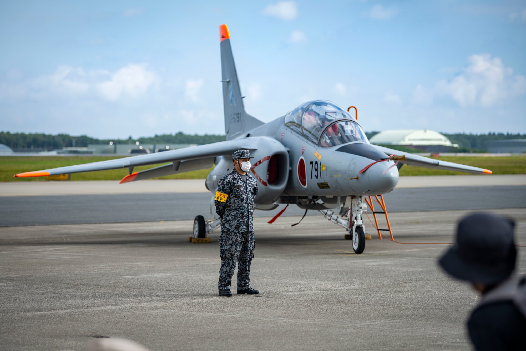 A Japanese military member stands in front of an aircraft