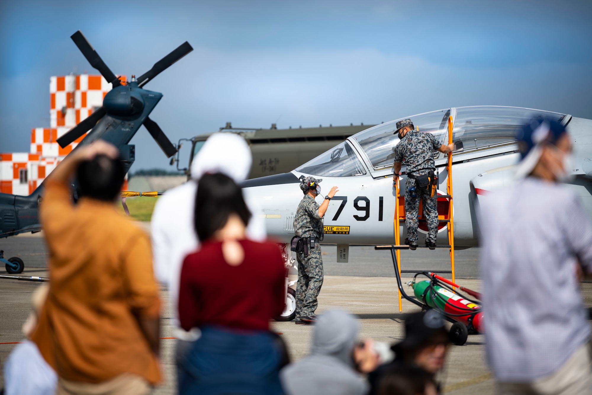 Japanese military members climb onto an aircraft