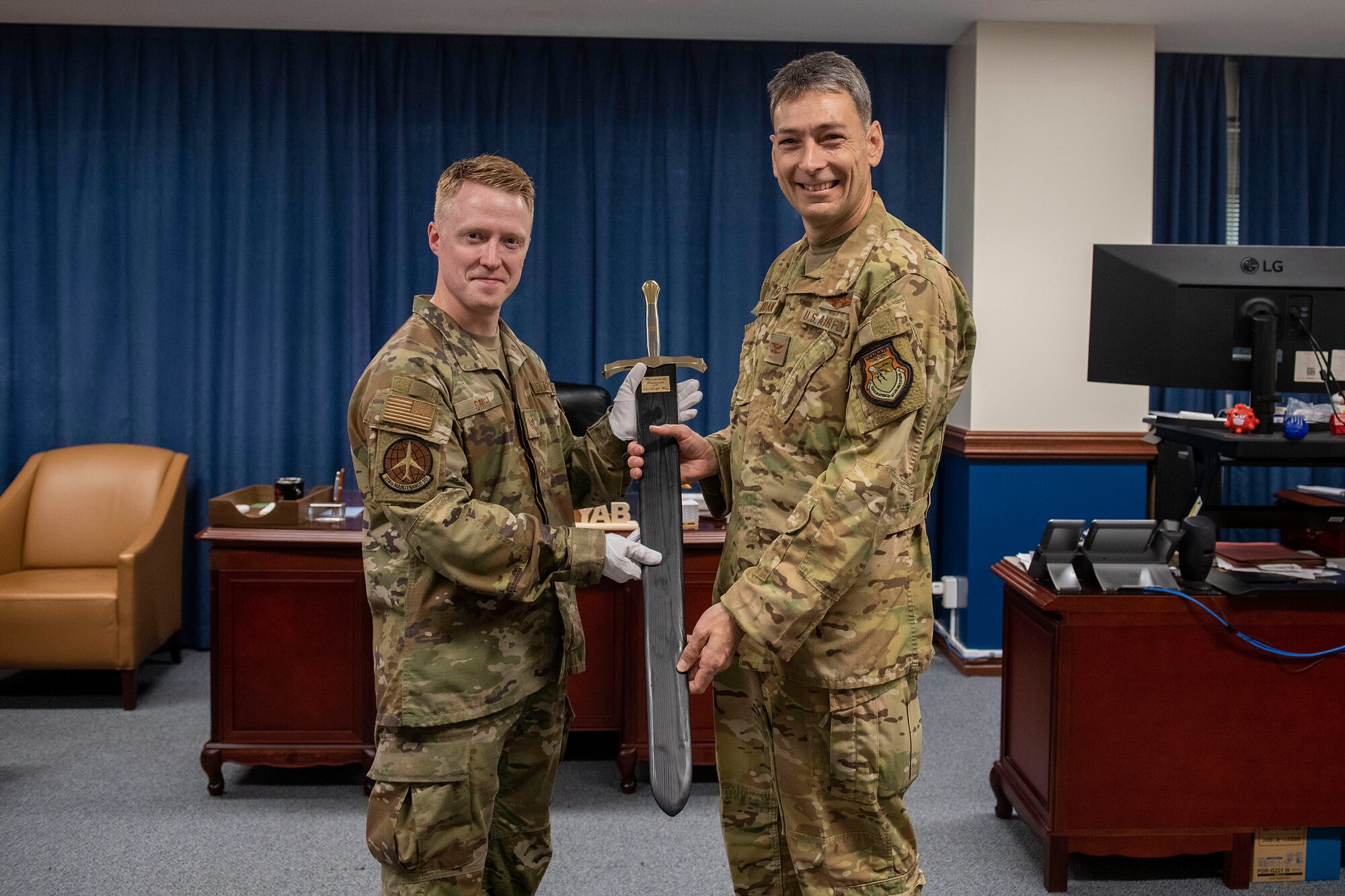 The Wing Commander stands with an Airmen and the sheathed Wing Ceremonial Sword