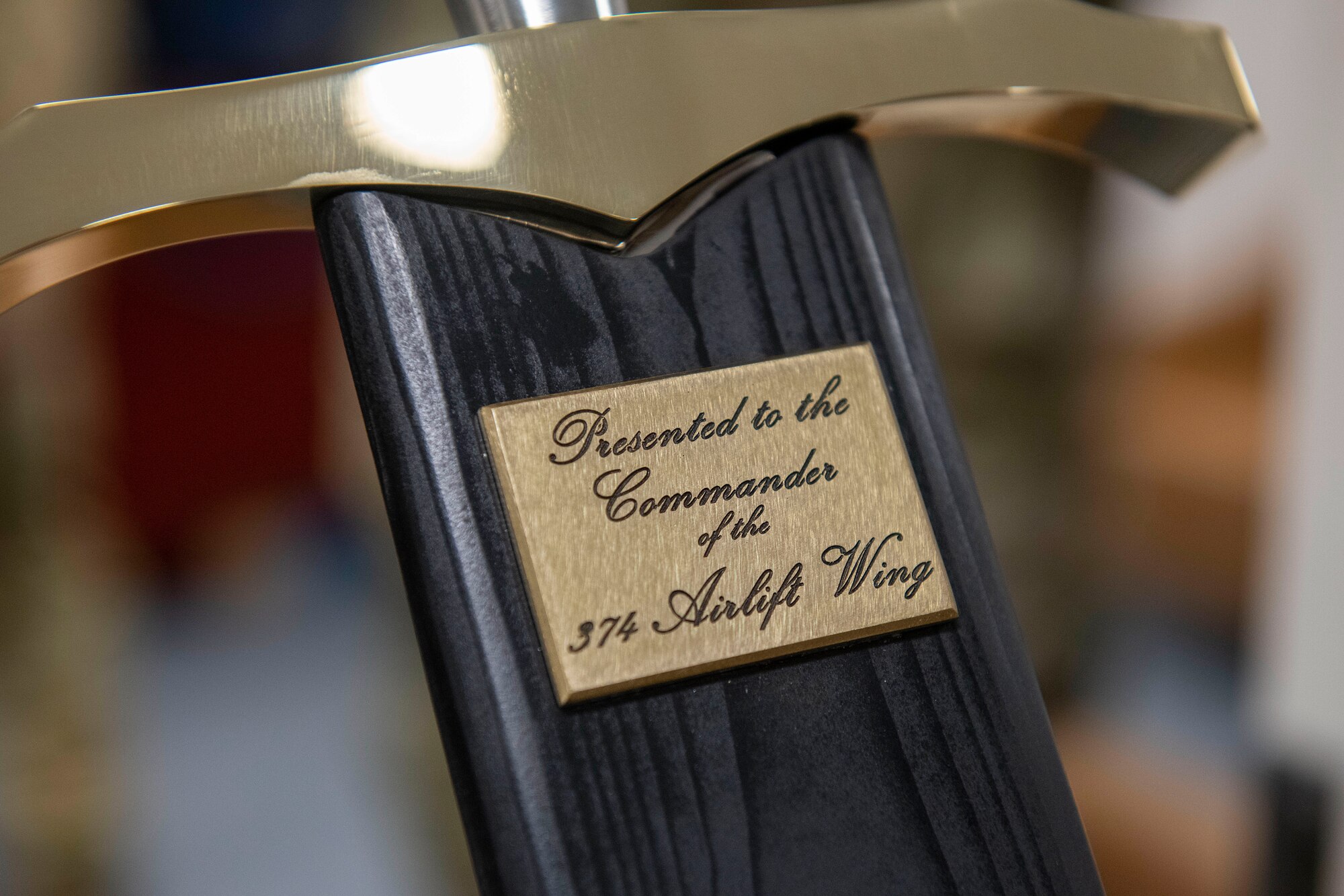 The words “Presented to the Commander of the 374th Airlift Wing” are engraved on the sheath of a sword