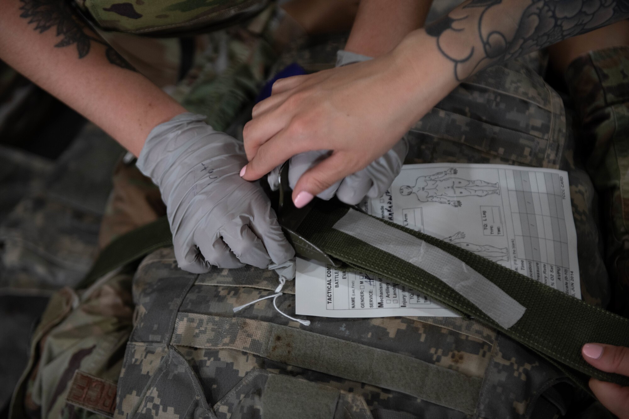 Airmen from the 379th Expeditionary Operational Medical Readiness Squadron secure a simulated casualty to a medical litter during Exercise Grand Shield 22-5 on Al Udeid Air Base, Qatar, Sept. 9, 2022. Simulated casualties were delivered to the hospital for further simulated treatment. (U.S. Air National Guard photo by Airman 1st Class Constantine Bambakidis)