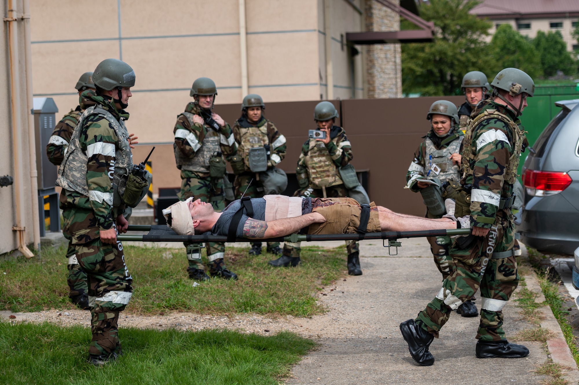 Wing inspection team members observe as U.S. Air Force Airman Samuel Baldwin (left or right), 51st Force Support Squadron and U.S. Air Force Staff Sgt. Ryan Breen (left or right), 51st Force Support Squadron shelter management team members, transport a simulated victim on a stretcher during a base-wide training scenario