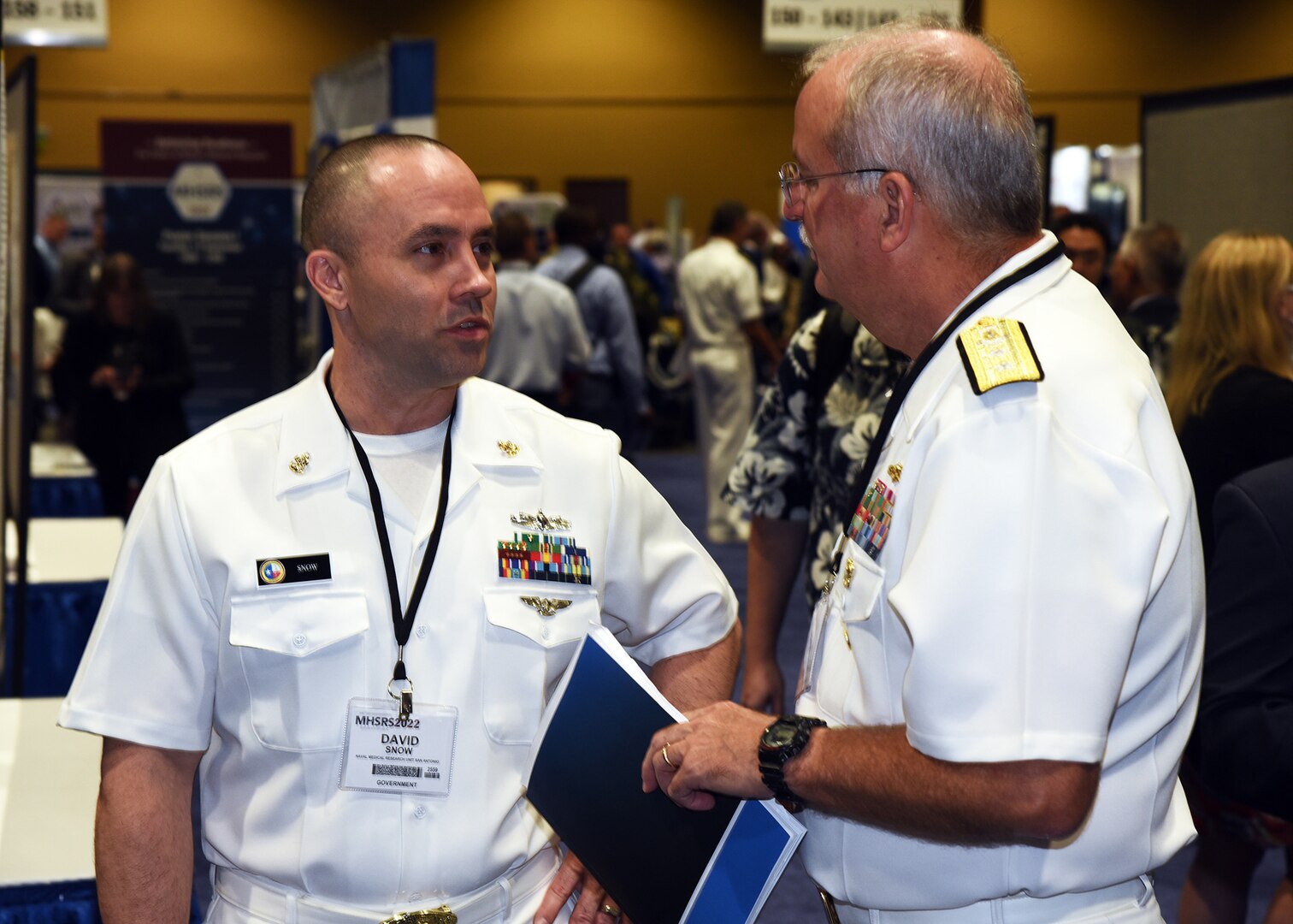 KISSIMMEE, Fla. – (Sept. 13, 2022) – Senior Chief Hospital Corpsman David Snow, of Mountain Top, Pa., senior enlisted leader assigned to Naval Medical Research Unit (NAMRU) San Antonio, speaks with the Surgeon General of the Navy, Rear. Adm. Bruce L. Gillingham during a poster session held on day two of the 2022 Military Health System Research Symposium (MHSRS) held at the Gaylord Palms Resort and Convention Center. The 2022 MHSRS brings together military, government, academia, and industry experts for four days of critical conversations and intensive idea sharing. Presenters will share their latest research findings and challenges on topics including combat casualty care, military operational medicine, clinical and rehabilitative medicine, medical simulation and information sciences, military infectious diseases, and the radiation health effects. NAMRU San Antonio is one of the leading research and development laboratories for the U.S. Navy under the Department of Defense and is one of eight subordinate research commands in the global network of laboratories operating under the Naval Medical Research Center in Silver Spring, Md.  Its mission is to conduct gap driven combat casualty care, craniofacial, and directed energy research to improve survival, operational readiness, and safety of DOD personnel engaged in routine and expeditionary operations. (U.S. Navy photo by Burrell Parmer, NAMRU San Antonio Public Affairs/Released)