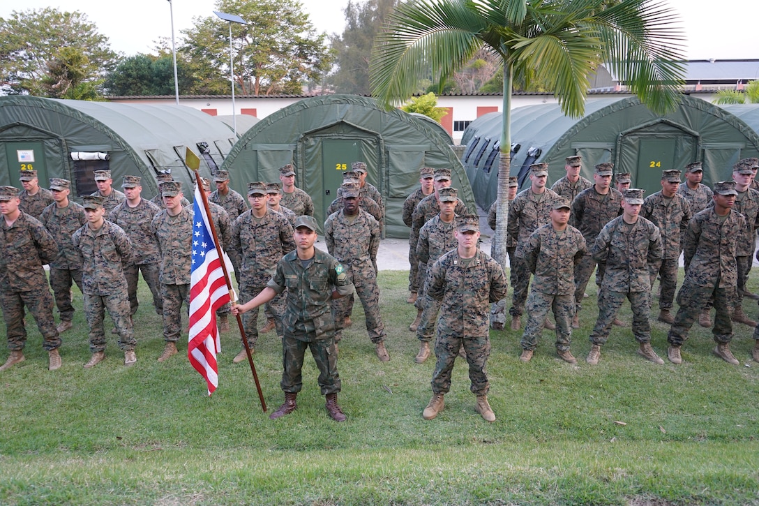 Brazilian marine Márcio Lopes de Moura Junior, left, 1st Creek Battalion, Brazilian Marine Corps, and U.S. Marine Corps Captain Trevor Strandh, right, commander of headquarters company, 25th Marine Regiment, 4th Marine Division, Marine Forces Reserve, stand before a formation of U.S. Marines during an address by the U.S. Secretary of the Navy Carlos Del Toro (not pictured) on the official opening day of exercise UNITAS LXIII at Ilha do Governador, Rio de Janeiro, Sept. 8, 2022. UNITAS is the world's longest-running annual multinational maritime exercise that brings together forces from 19 countries to include Brazil, Cameroon, Chile, Colombia, Dominican Republic, Ecuador, France, Guyana, Jamaica, Mexico, Namibia, Panama, Paraguay, Peru, South Korea, Spain, United Kingdom, Uruguay, and the United States. The exercise focuses on enhancing interoperability among multiple nations and joint forces during littoral and amphibious operations in order to build on existing regional partnerships and create new enduring relationships that promote peace, stability, and prosperity in the U.S. Southern Command’s area of responsibility. (U.S. Marine Corps photo by Major Jeremy Wheeler)