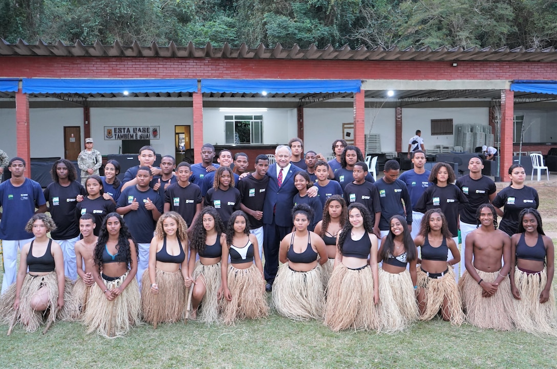 U.S. Secretary of the Navy Carlos Del Toro, poses for a photograph with the teenagers of the Brazilian Forcas no Esporte (Forces in Sport) program following their Brazilian jiu-jitsu inspired dance demonstration on the official opening day of exercise UNITAS LXIII at Ilha do Governador, Rio de Janeiro, Sept. 8, 2022. The Brazilian Forcas no Esporte program aims to reduce social risks of vulnerable young Brazilians, strengthen bonds of citizenship, inclusion, and social integration. The SECNAV toured the training location to visit with the host nation Brazilians as well as Marines from twelve partnered nations who are participating in the exercise. UNITAS is the world’s longest-running annual multinational maritime exercise that focuses on enhancing interoperability among multiple nations and joint forces during littoral and amphibious operations in order to build on existing regional partnerships and create new enduring relationships that promote peace, stability and prosperity in the U.S. Southern Command’s area of responsibility. (U.S. Marine Corps photo by Maj. Jeremy Wheeler)