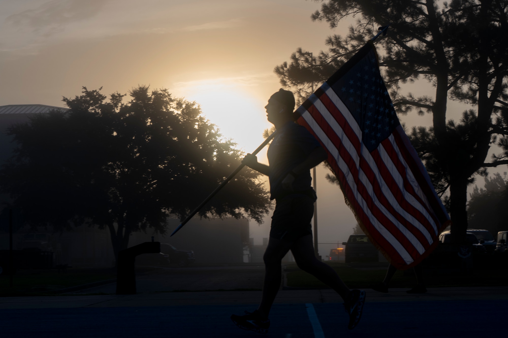 Airman runs with U.S. flag at sunrise.