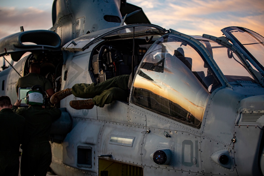 Cpl. Kevin Yoon (feet), an avionics technician, with Marine Light Attack Helicopter Squadron - 773, 4th Marine Aircraft Wing, Marine Forces Reserve in support of Special Purpose Marine Air-Ground Task Force UNITAS LXIII, conducts routine maintenance on an AH-1Z Viper at São Pedro da Aldeia, Brazil, during exercise UNITAS LXIII, Sept. 7, 2022. UNITAS is the world's longest-running annual multinational maritime exercise that focuses on enhancing interoperability among multiple nations and joint forces during littoral and amphibious operations in order to build on existing regional partnerships and create new enduring relationships that promote peace, stability, and prosperity in the U.S. Southern Command’s area of responsibility. Yoon is a native of Sacramento, CA. (U.S. Marine Corps photo by 1st Lt. Mark L. Andries)