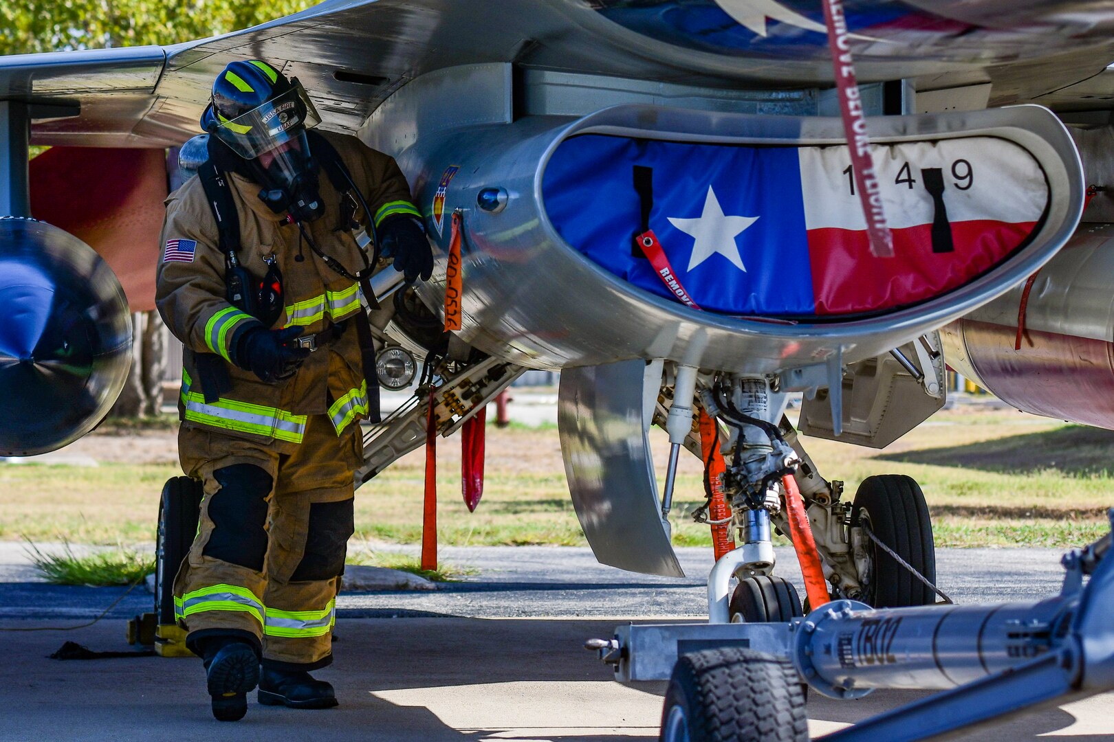 Michael Hillard, 902nd Civil Engineer Squadron firefighter, ensures the aircraft is safe prior to extracting the pilot during an emergency response egress exercise for an F-16 Fighting Falcon at Joint Base San Antonio-Lackland Aug. 19, 2022.