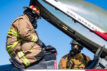 Andrew Sanchez (left), 902nd Civil Engineer Squadron lead firefighter, and Michael Hillard (right) 902nd CES firefighter, participate in an emergency response egress exercise for an F-16 Fighting Falcon at Joint Base San Antonio-Lackland, Texas, Aug. 19, 2022.
