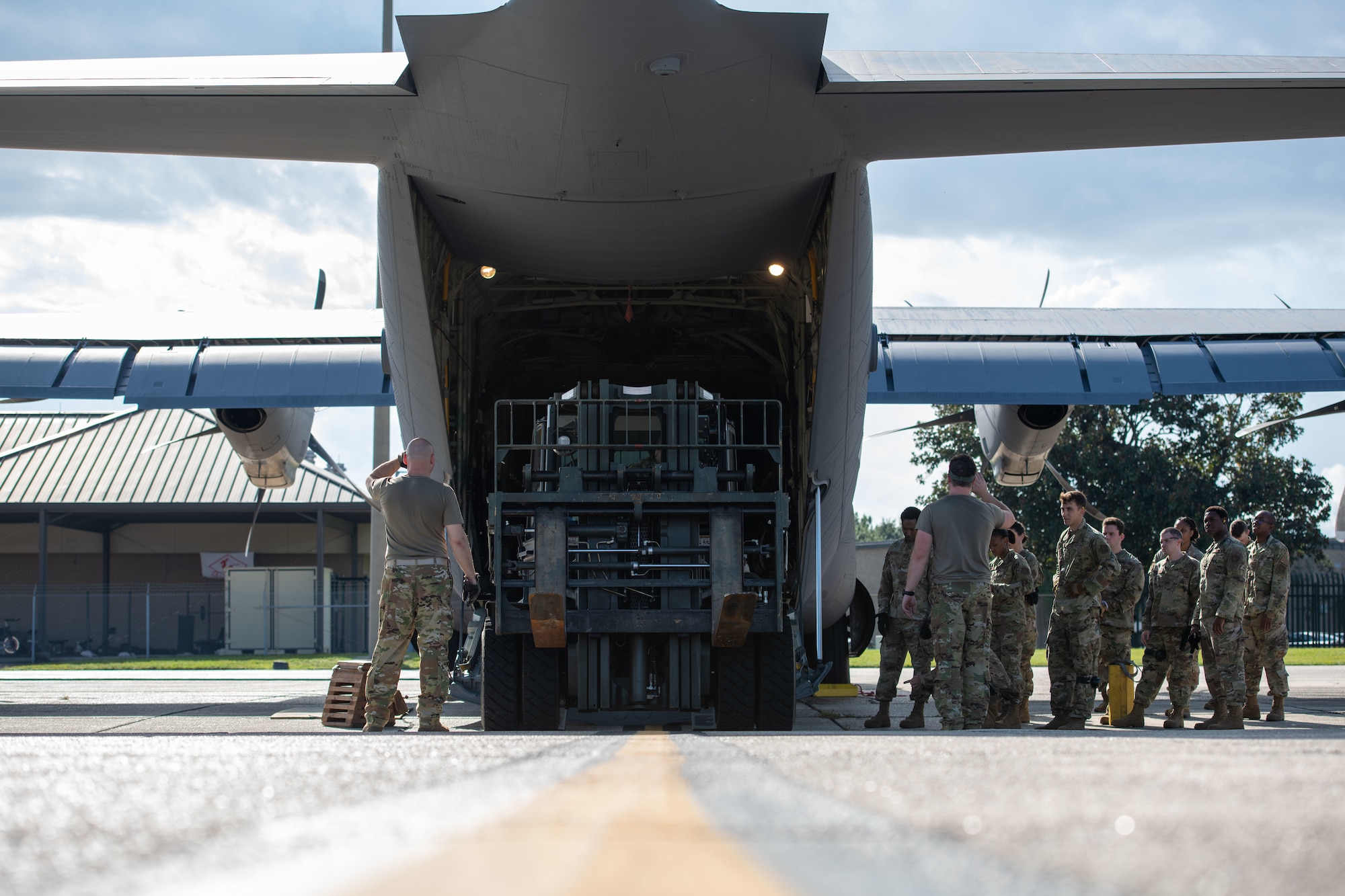 Callais backs a forklift onto a C-130j while Airmen watch