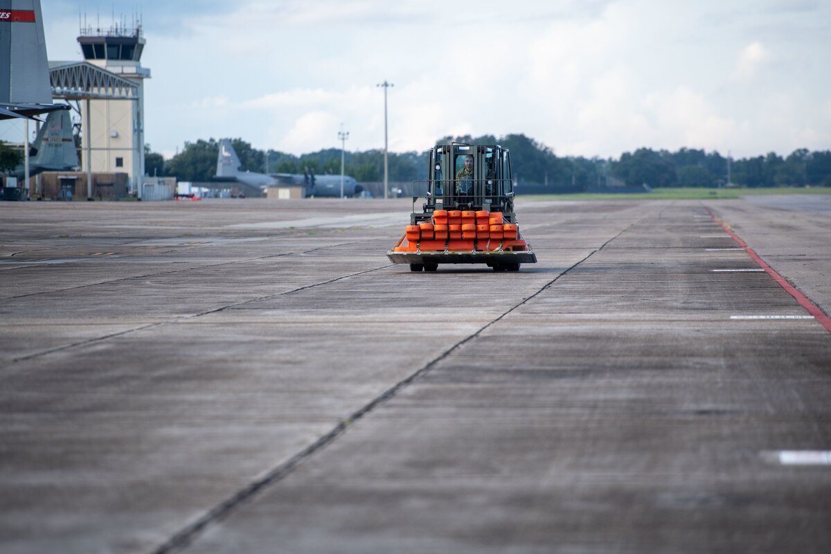 A forklift carrying cargo drives on the flightline