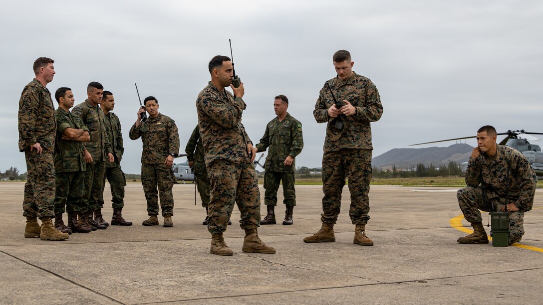 U.S. Marines with 4th Air Naval Gunfire Liaison Company, Force Headquarters Group, Marine Forces Reserve, in support of Special Purpose Marine Air-Ground Task Force UNITAS LXIII, talk through communications operations with Brazilian Marines in São Pedro da Aldeia, Brazil, during exercise UNITAS LXIII, Sept. 4, 2022. U.S. Marines and Brazilian Marines used this time to convey communication procedures and safety actions before flights began. UNITAS trains forces to conduct joint maritime operations through the execution of anti-surface, anti-submarine, anti-air, amphibious and electronic warfare operations that enhance warfighting proficiency and increase interoperability among participating naval and marine forces. (U.S. Marine Corps photo by Cpl. Jonathan L. Gonzalez)
