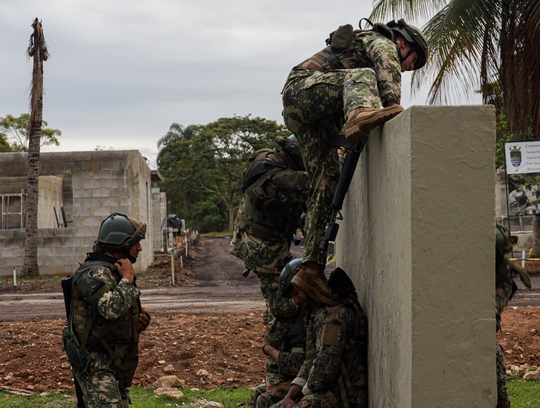 Service members from Jamaica, Paraguay, and the United States of America assist one another in scaling a wall while conducting urban operations training during UNITAS LXIII, in Ilha do Governador, Rio de Janeiro, Sept. 5, 2022. UNITAS is the world’s longest-running annual multinational maritime exercise that focuses on enhancing interoperability among multiple nations and joint forces during littoral and amphibious operations in order to build on existing regional partnerships and create new enduring relationships that promote peace, stability and prosperity in the U.S. Southern Command’s area of responsibility. (U.S. Marine Corps photo by Lance Cpl. Trystan Taft)