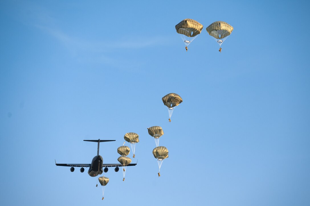 A group of soldiers parachute from a plane.
