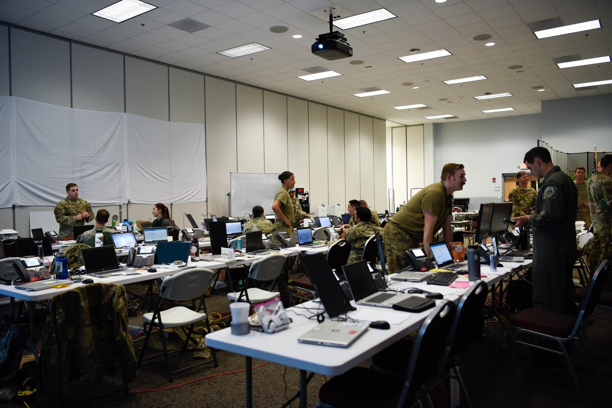 photo of US military working at computers on long rows of white tables