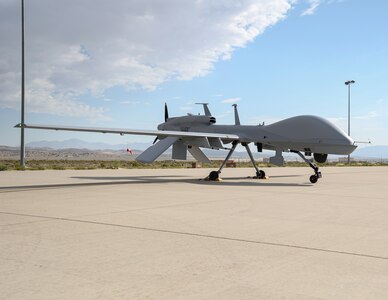 A Gray Eagle MQ-1 unmanned aerial vehicle passes in front of the KC-135R Stratotanker