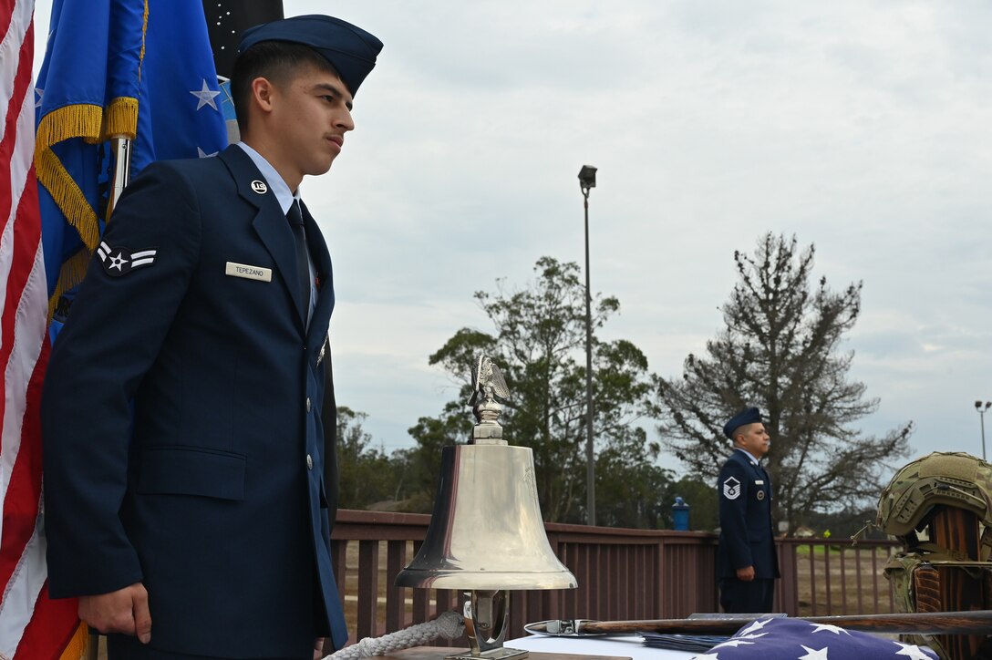 An airman stands by, ready to ring a bell on a table