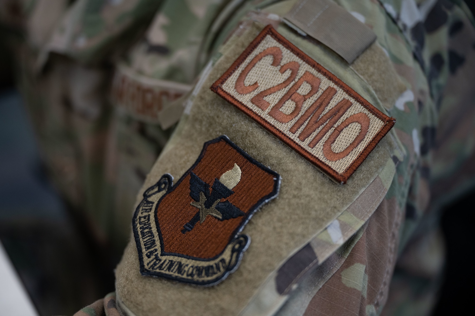 A patch with the code C2BMO rests on the uniform of an Airman.
