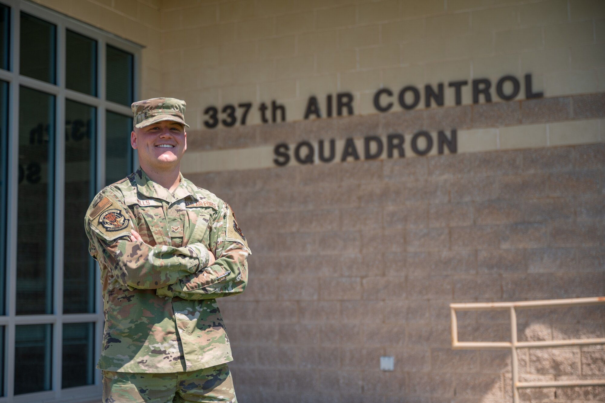 An Airman poses in front of a building for a photo.