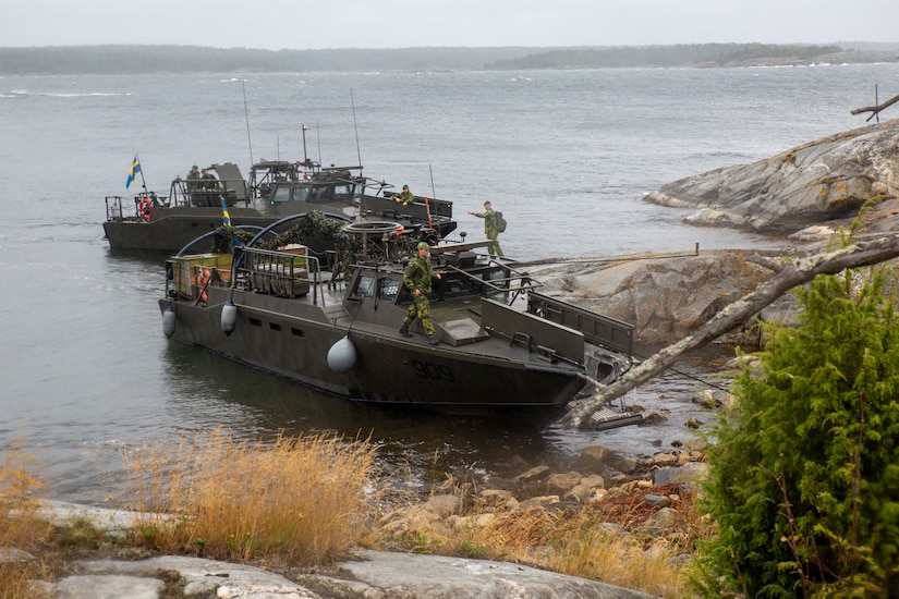 Service members walk on the decks of two boats.