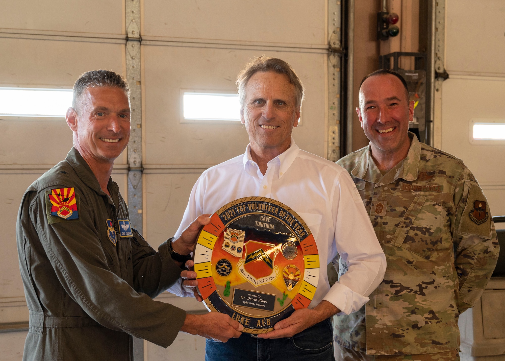 U.S. Air Force Brig. Gen. Gregory Kreuder, 56th Fighter Wing commander, and U.S. Air Force Chief Master Sgt. Daniel Weimer, 56th Fighter Wing command chief, presents the 2021 Fighter Country Foundation Volunteer Award to Mr. Darrell Wilson, founder and principal of Hilgart Wilson, during Luke Air Force Base’s Supporter Appreciation Day event, May 13, 2022, at Luke AFB, Arizona.