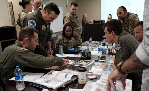 photo of a group of US military sitting and standing around a table