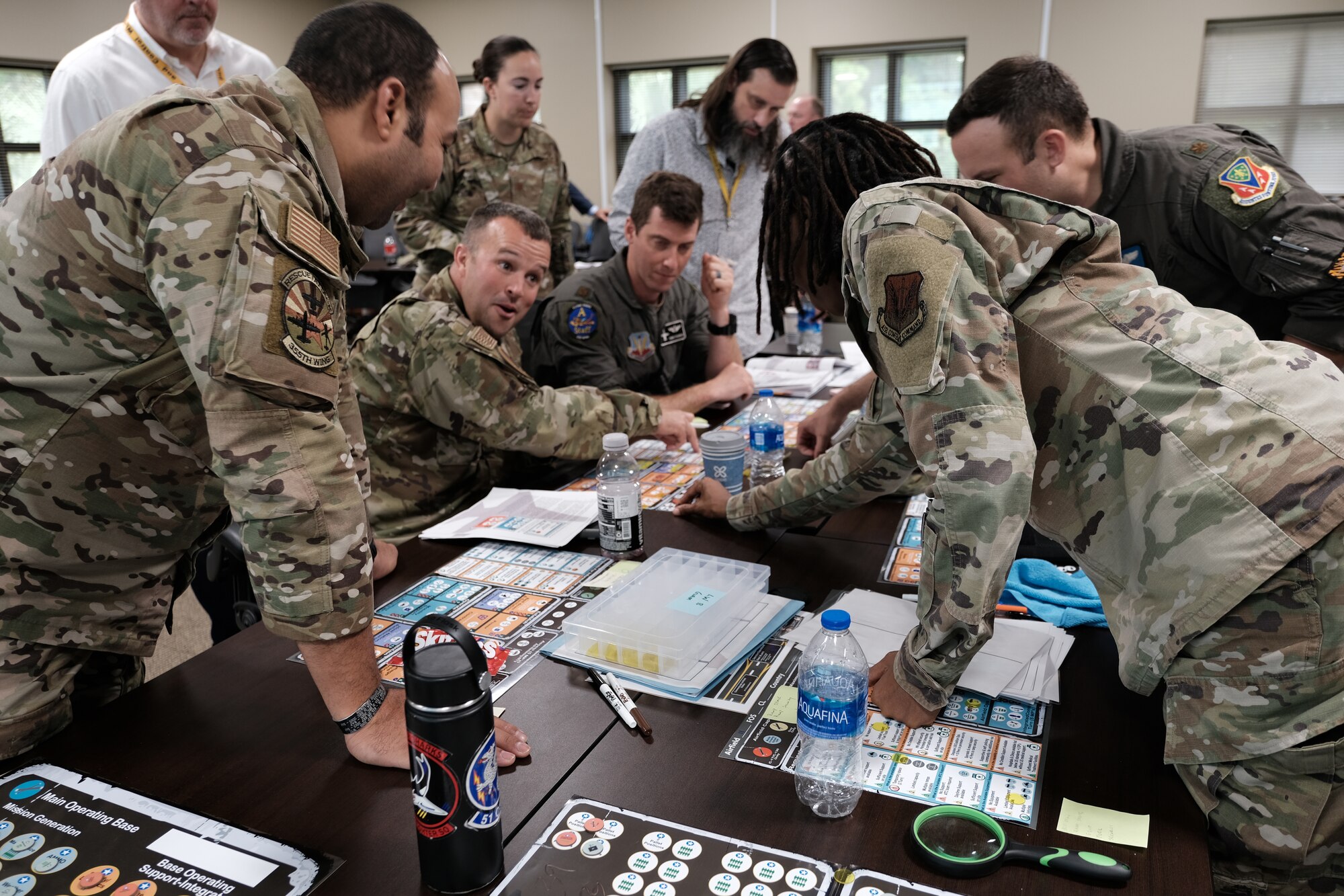 photo of a group of US military standing and sitting around a table looking at map