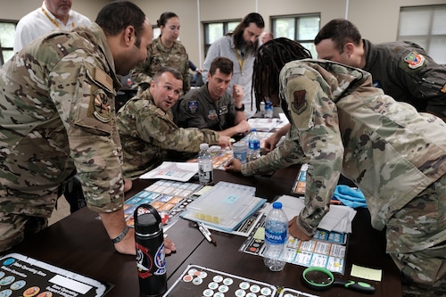 photo of a group of US military standing and sitting around a table looking at map