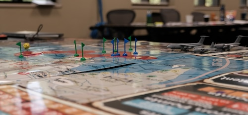 photo of a group of US military standing and sitting around a table looking at map