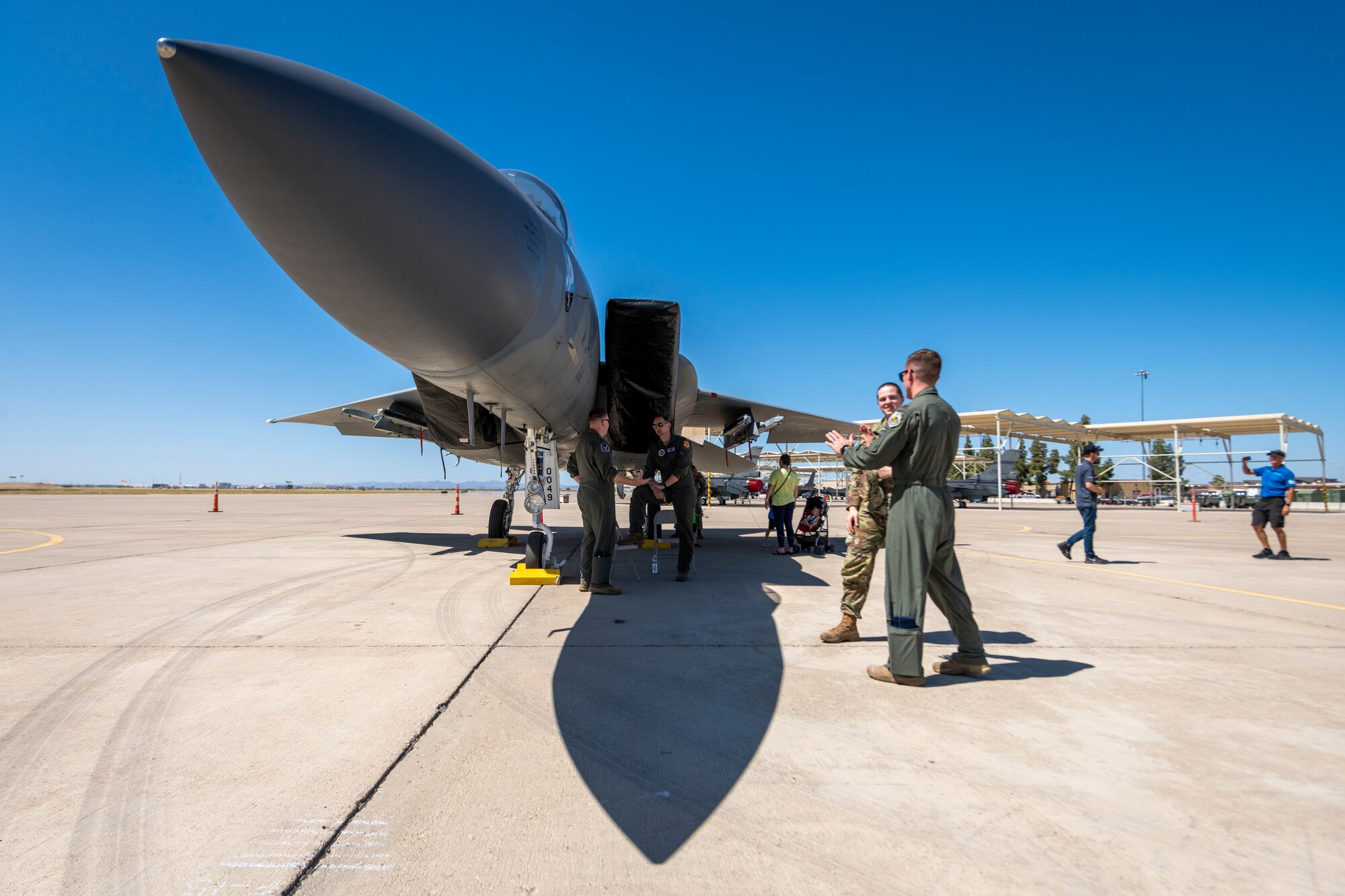 U.S. Air Force pilots talk beneath an F-15C Eagle fighter jet, assigned to the 173rd Fighter Wing, Kingsley Field, Oregon, during the Luke Air Force Base Supporter Appreciation Day event, May 13, 2022, at Luke AFB, Arizona.