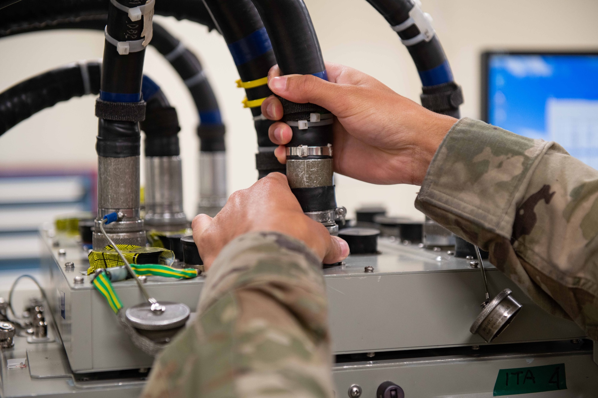 An Airman plugs in a big wire to a machine