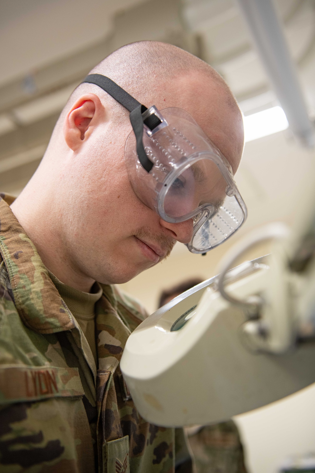 An Airman looks through a magnifying glass at a soldering station