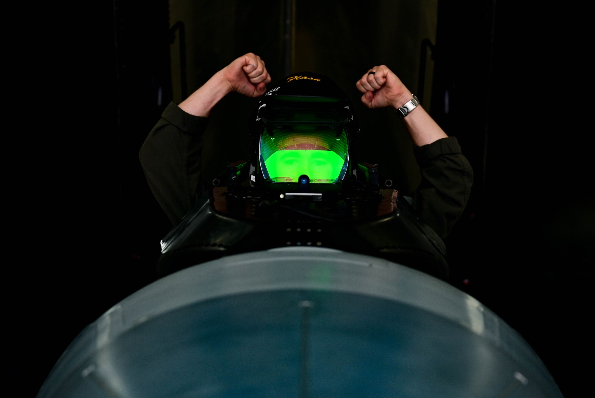 Pilot in aircraft raising arms into air.