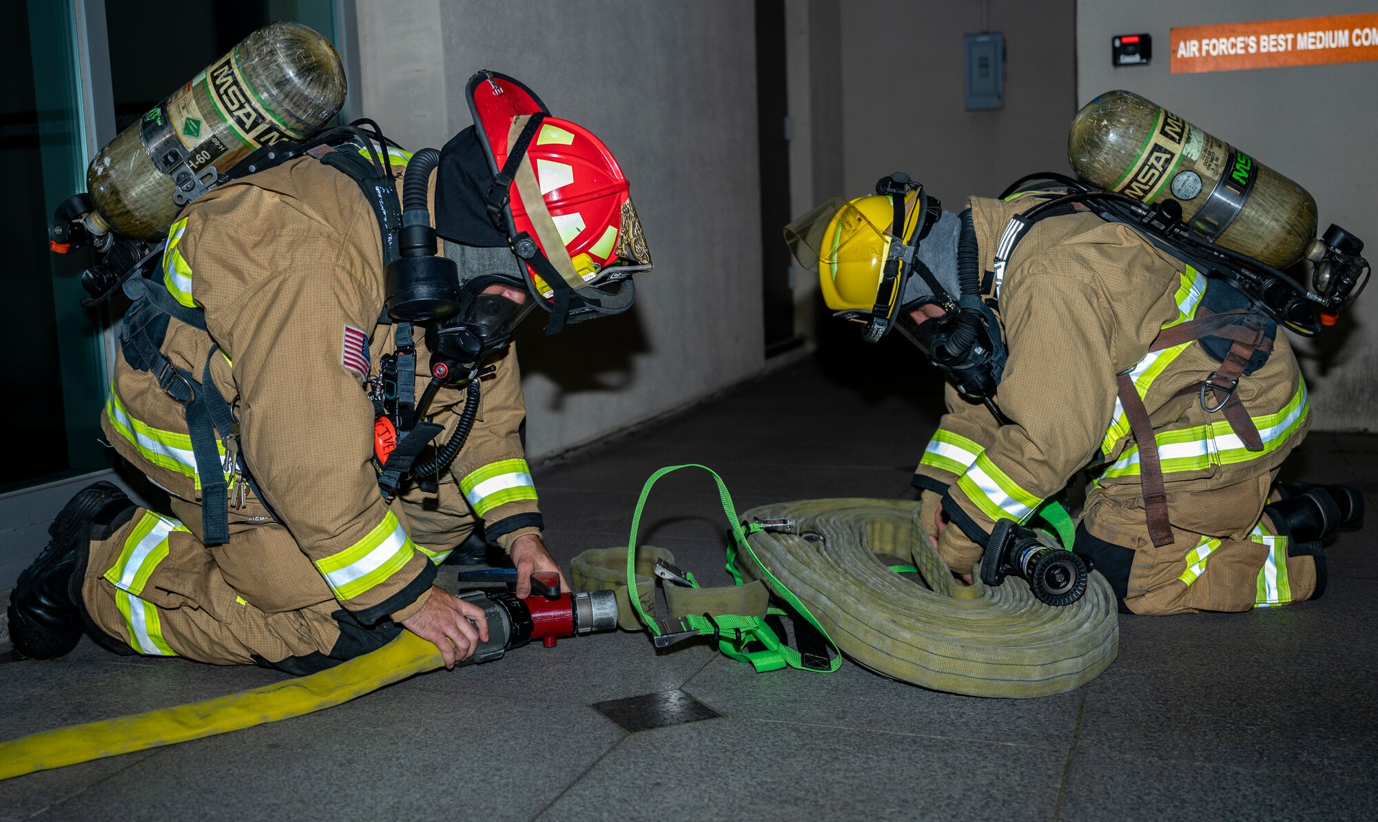 U.S. Air Force Airman 1st Class Joey Vue and U.S. Air Force Staff Sgt. Larry McIver, 51st Civil Engineer Squadron firefighters, arrange a hose during a fire response training scenario at Osan Air Base, Republic of Korea, Sept. 14, 2022.