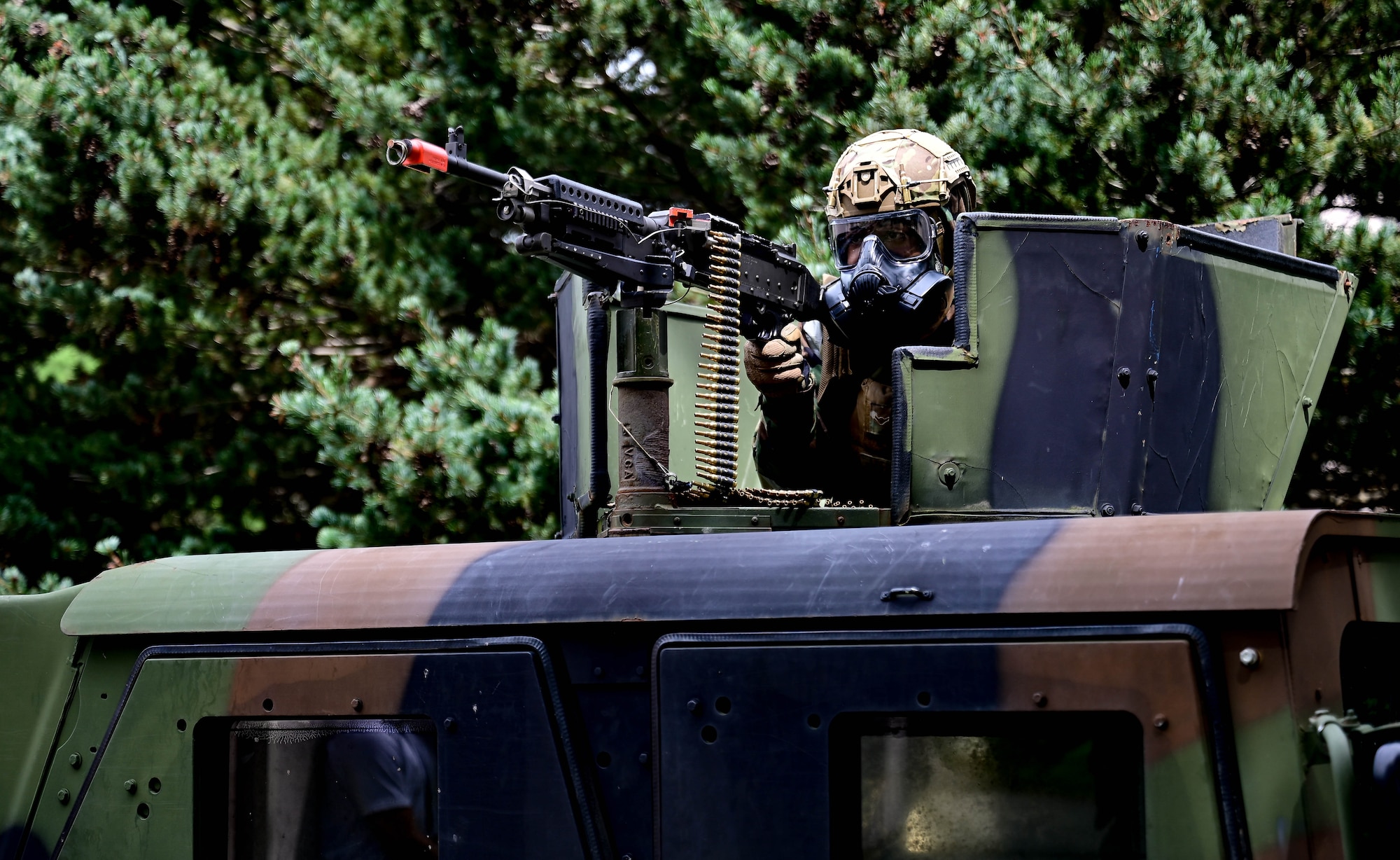 Man in chemical gear, mans armored vehicle turret.