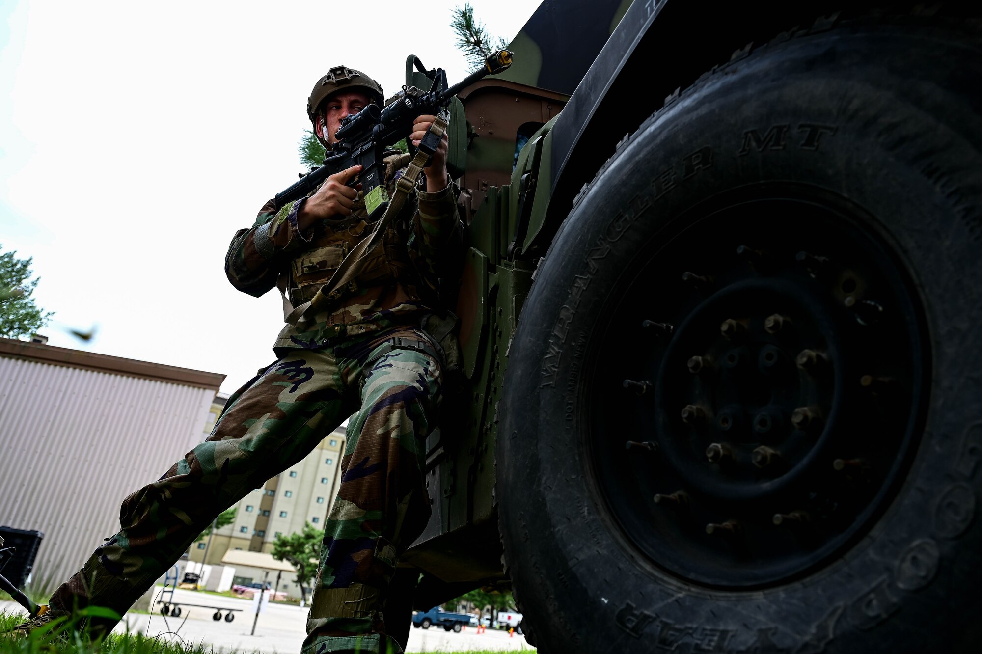 Man with weapon leans on vehicle.