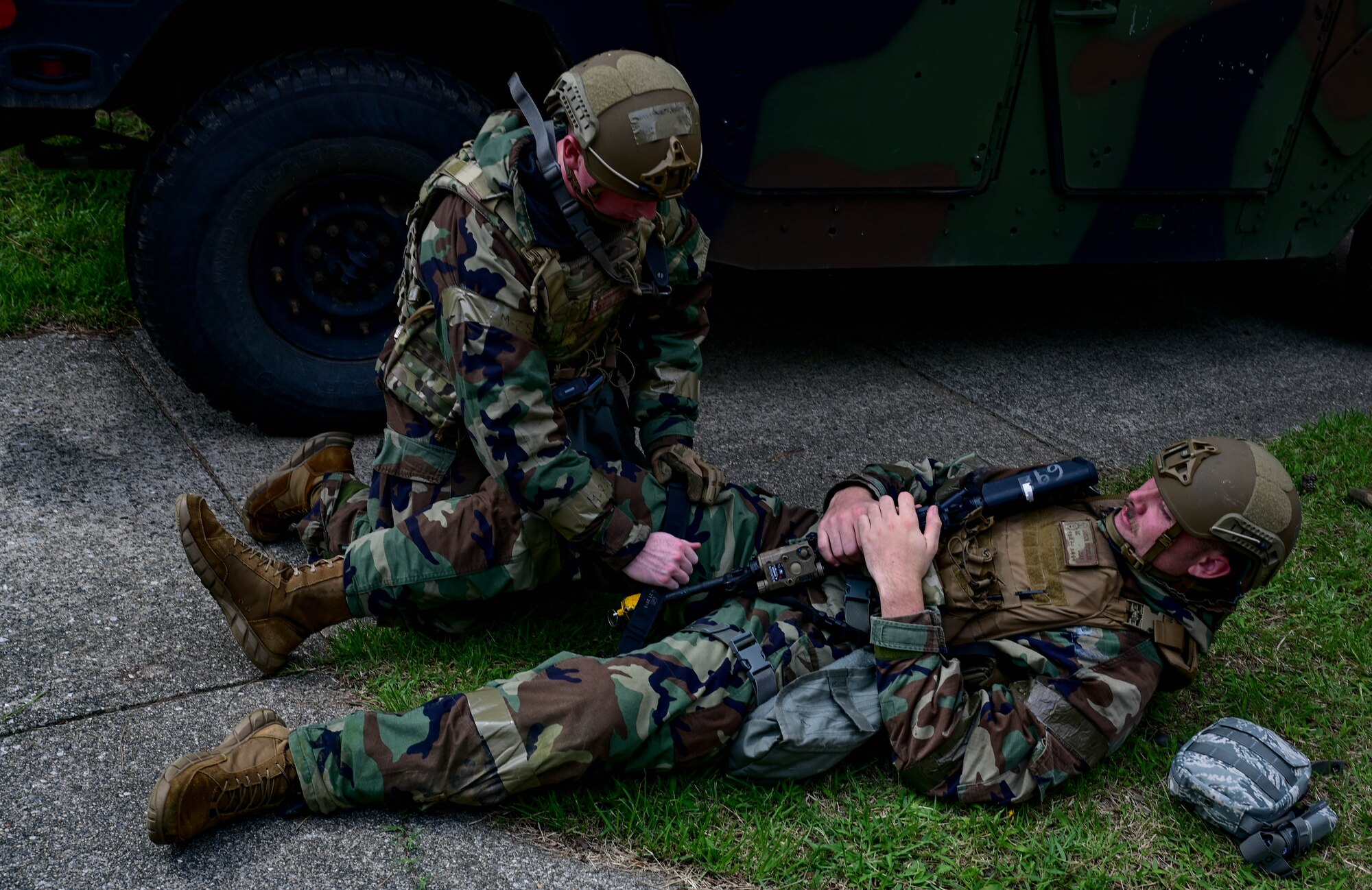 Airmen places tourniquet on another.