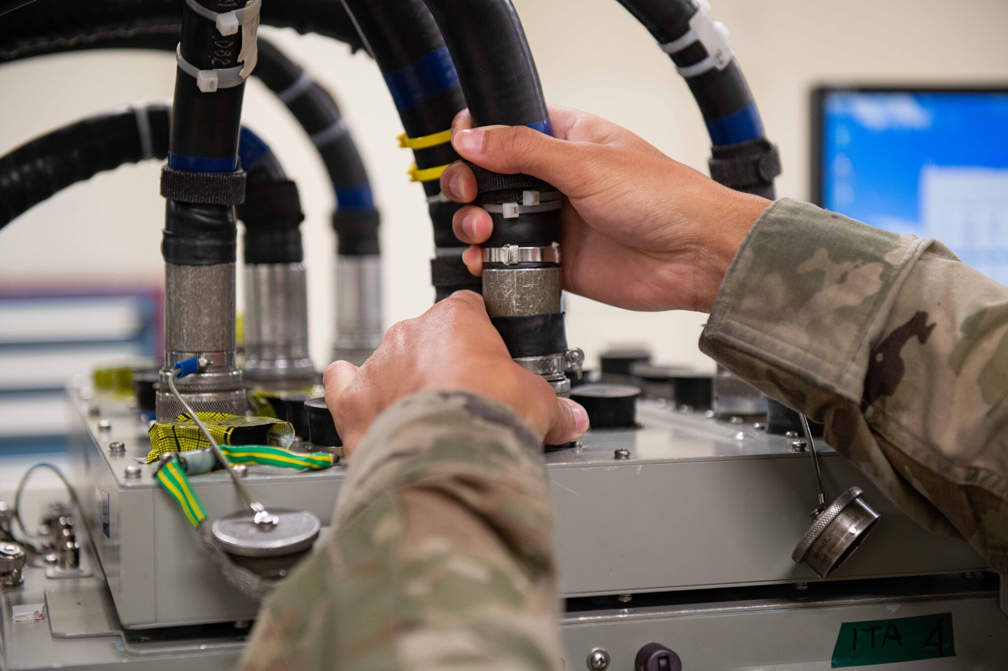 An Airman plugs in a big wire to a machine