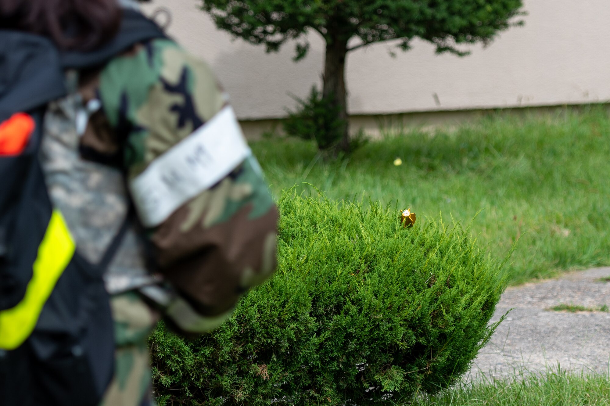 U.S. Air Force Senior Airman Nancy Prue, 51st Force Support Squadron shelter management team member, discovers a simulated unexploded ordnance (UXO) in a bush during a post-attack reconnaissance sweep as part of a base-wide training event