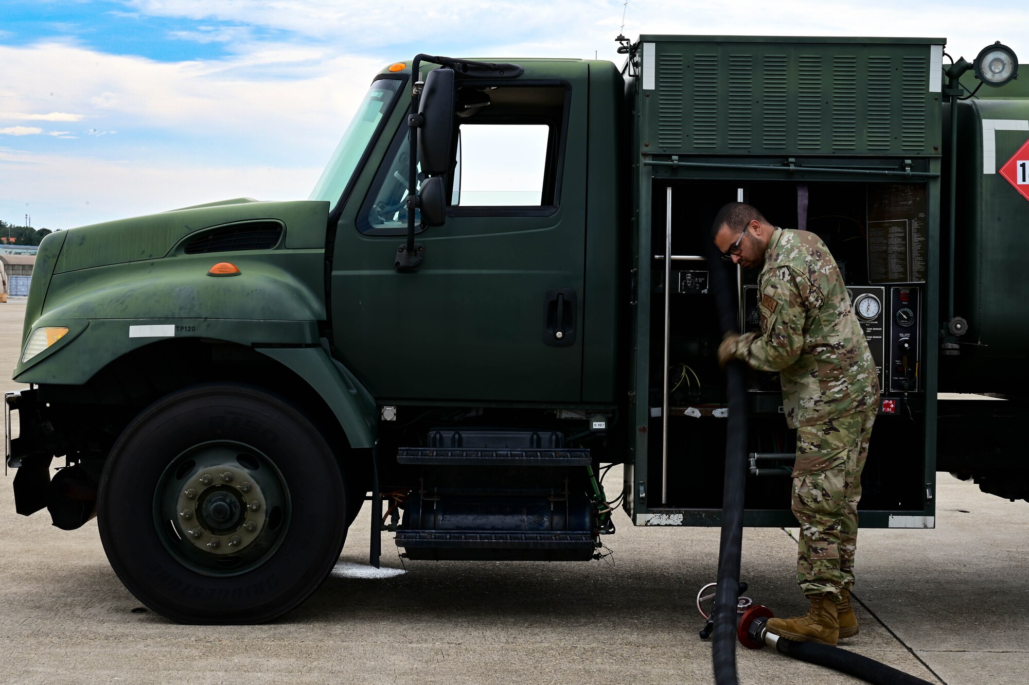 Man pulling fuel line to truck.