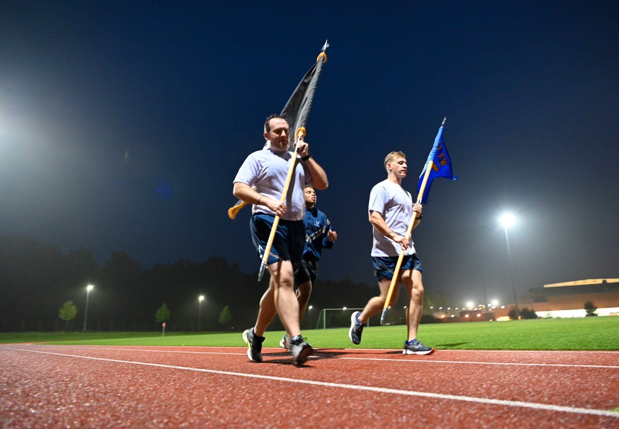 Airmen run with the POW.MIA flag at night.