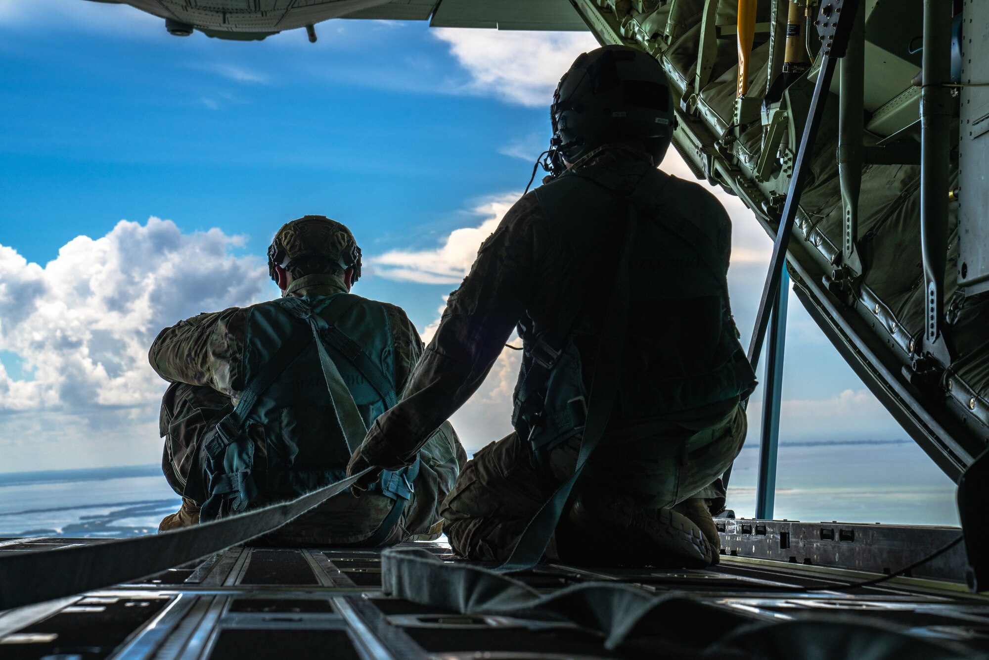U.S. Air Force Senior Airman Cameron Stewart, left, Air Force Special Operations Command administrator, sits on the loading ramp of an HC-130J Combat King II aircraft assigned to the 920th Rescue Wing, Patrick Space Force Base, Florida, over Tampa, Florida, Sept. 1, 2022.