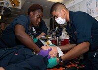 220916-N-TT639-1005 PHILIPPINE SEA (Sept. 16, 2022) – Hospital Corpsman 3rd Class Kamala Reidallen, from West Palm Beach, Florida, left, and Hospital Corpsman 2nd Class Benny Macanas, assigned to Fleet Surgical Team (FST) 7, from San Diego, apply a neck brace to a simulated casualty during a medical training team evolution aboard amphibious assault carrier USS Tripoli (LHA 7) Sept. 16, 2022. Tripoli is operating in the U.S. 7th Fleet area of operations to enhance interoperability with allies and partners and serve as a ready response force to defend peace and maintain stability in the Indo-Pacific region. (U.S. Navy photo by Mass Communication Specialist 3rd Class Christopher Sypert)