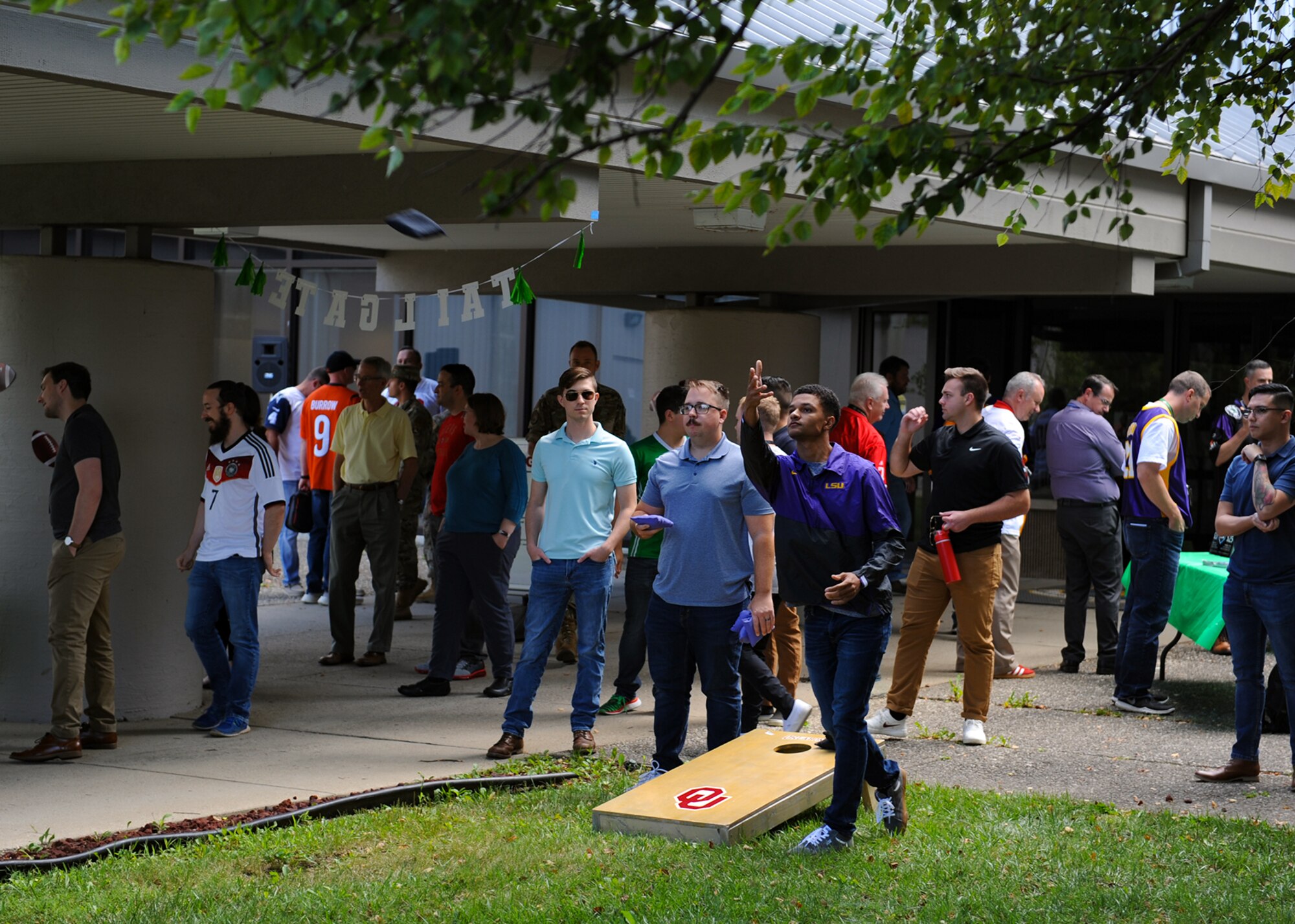 Members from the National Air and Space Intelligence Center relax by playing a game of corn hole during NASIC’s block party at Wright-Patterson AFB, Ohio, Sept. 8, 2022. Team NASIC members were authorized to wear their favorite jersey to represent their “home” team for this block party.