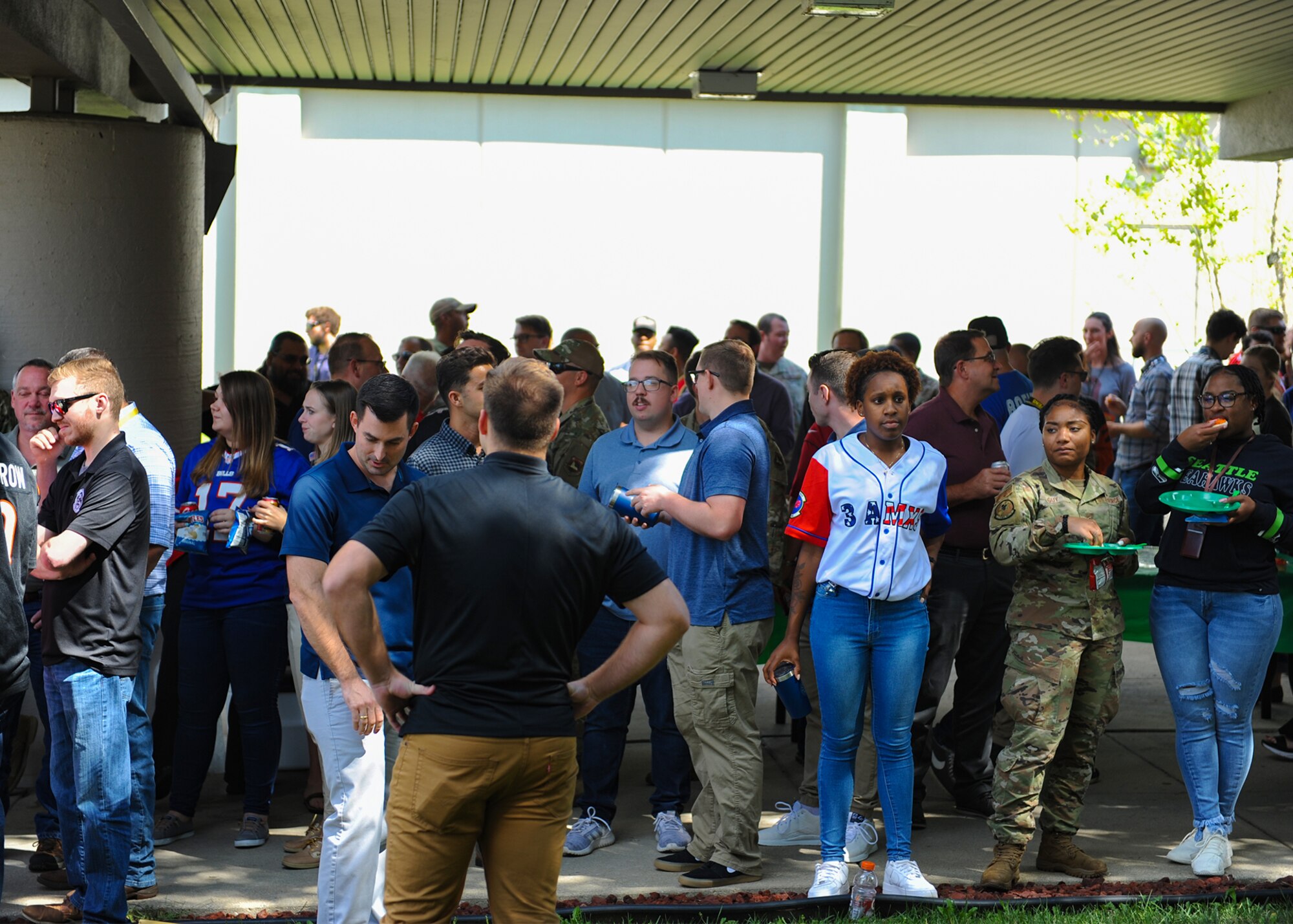 Members from the National Air and Space Intelligence Center eat and converse with one another during NASIC’s block party at Wright-Patterson AFB, Ohio, Sept. 8, 2022. Team NASIC members were authorized to wear their favorite jersey to represent their “home” team for this block party.