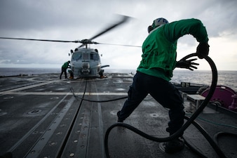 Aviation Structural Mechanic 3rd Class Francis Oteng retracts a fuel line from an MH-60R Sea Hawk helicopter aboard USS Normandy (CG 60).