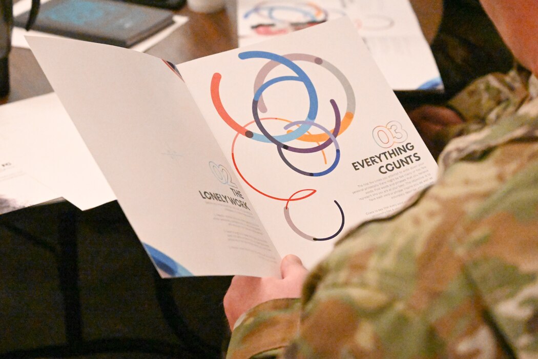 An Airman holds a program with training information.