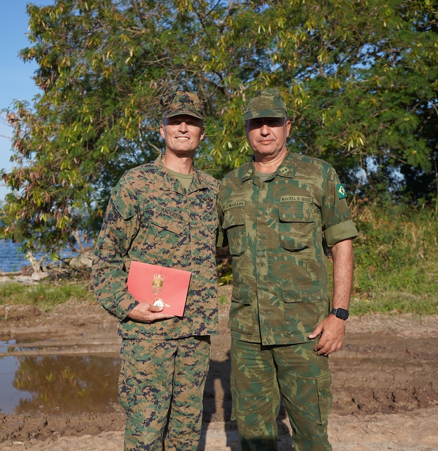 Brig. Gen. Len "Loni" Anderson, left, commanding general of 4th Marine Aircraft Wing, Marine Forces Reserve, received a personal letter and coin from Contra-Almirante Marcelo Guimarães Dias (Rear Adm. Brazilian Marine Corps), right, commander of Brazil’s Amphibious Division, following a tour of the training areas during UNITAS LXIII at Ilha do Governador, Rio de Janeiro, Sept. 6, 2022.  The exchange of a gift is indicative of the relationships built during the span of 63 iterations of exercise UNITAS. UNITAS, which is Latin for ‘unity’ trains forces from across the globe in South America to conduct joint maritime operations through the execution of anti-surface, anti-submarine, anti-air, amphibious, and electronic warfare operations that enhance warfighting proficiency and increase interoperability among participating navy and marine forces. (U.S. Marine Corps photo by Maj. Jeremy Wheeler)