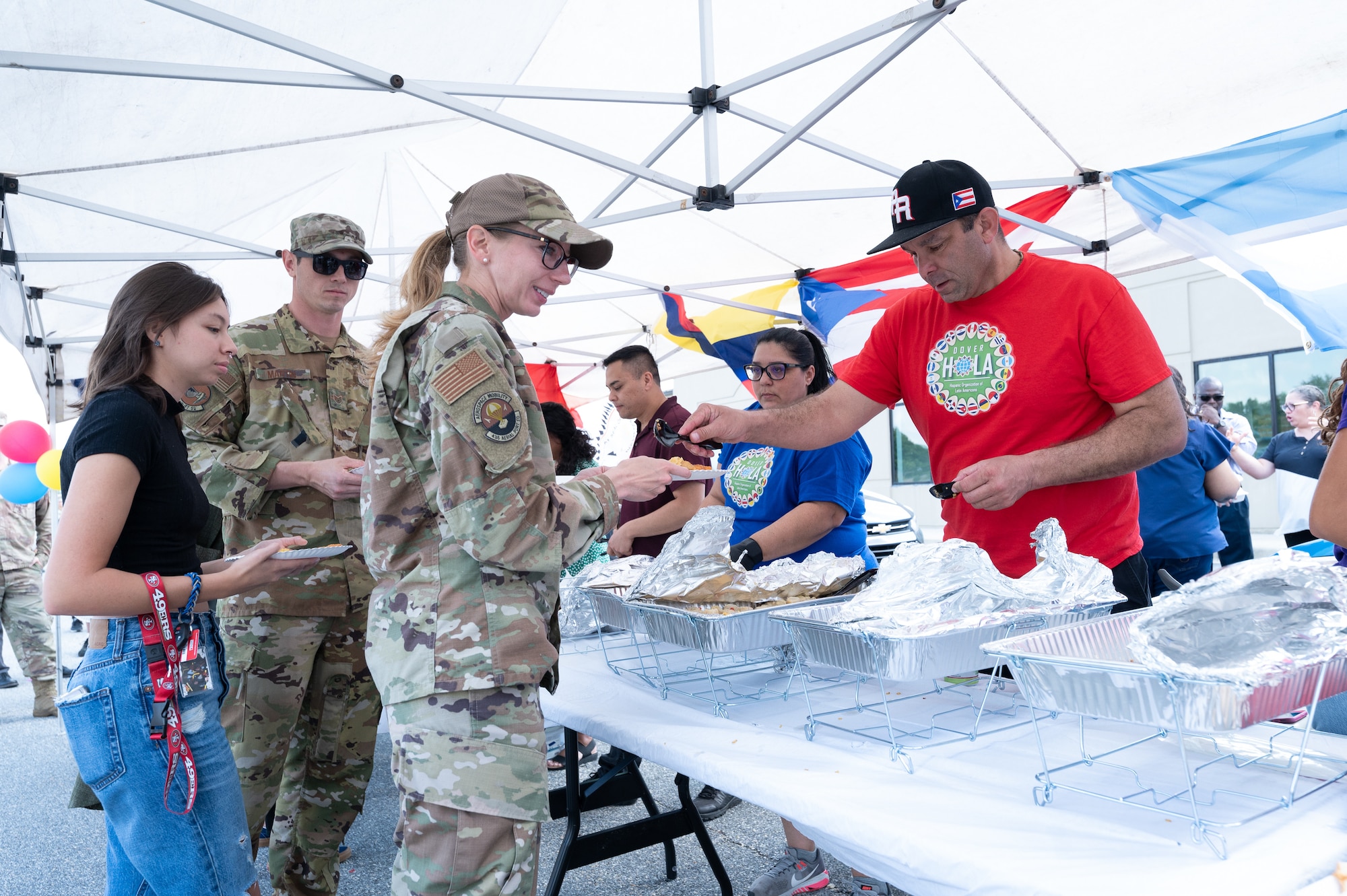 Master Sgt. Anthony Velazquez, 436th Airlift Wing noncommissioned officer in charge of inspections and exercises, serves Puerto Rican cuisine samples to attendees of the Hispanic Heritage Month Block Party on Dover Air Force Base, Delaware, Sept. 15, 2022. The party featured food, table displays of Latin American culture and DJs playing Latin American music. (U.S. Air Force photo by Mauricio Campino)